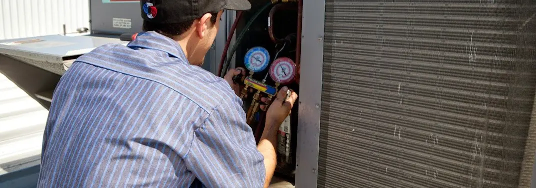 HVAC technician servicing a condenser unit in Tiffin